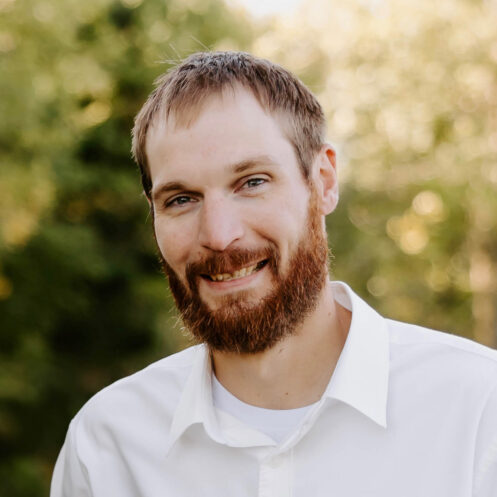 Allied Construction team member outdoors, smiling in a white dress shirt.
