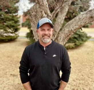 Allied Construction crew member standing outdoors with trees in background.