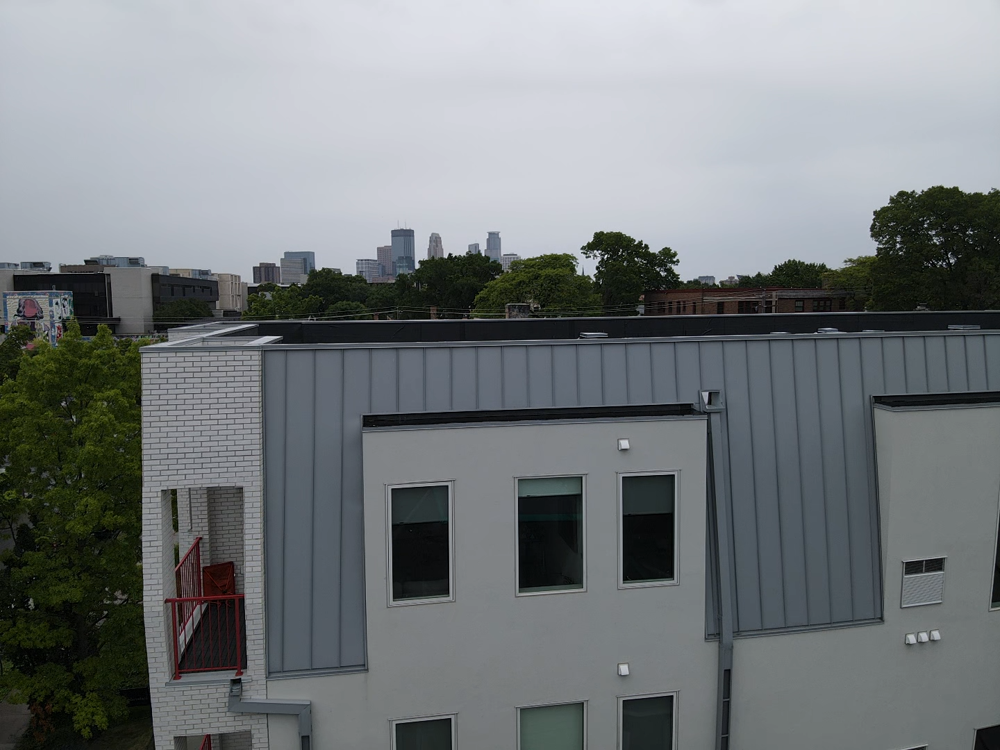 Close-up view of new flat roof installation with metal wall caps and Minneapolis skyline behind.