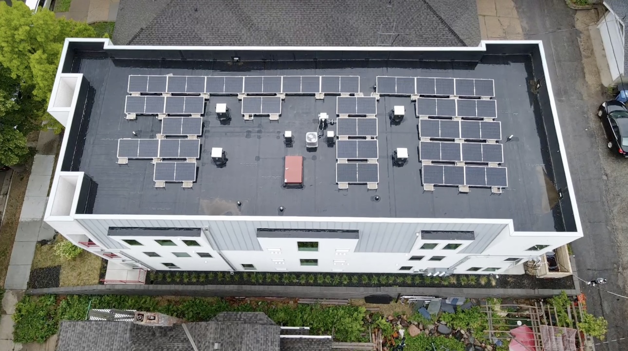 Aerial top-down view of a newly installed flat roof with solar panels on a multi-family building in Minneapolis.