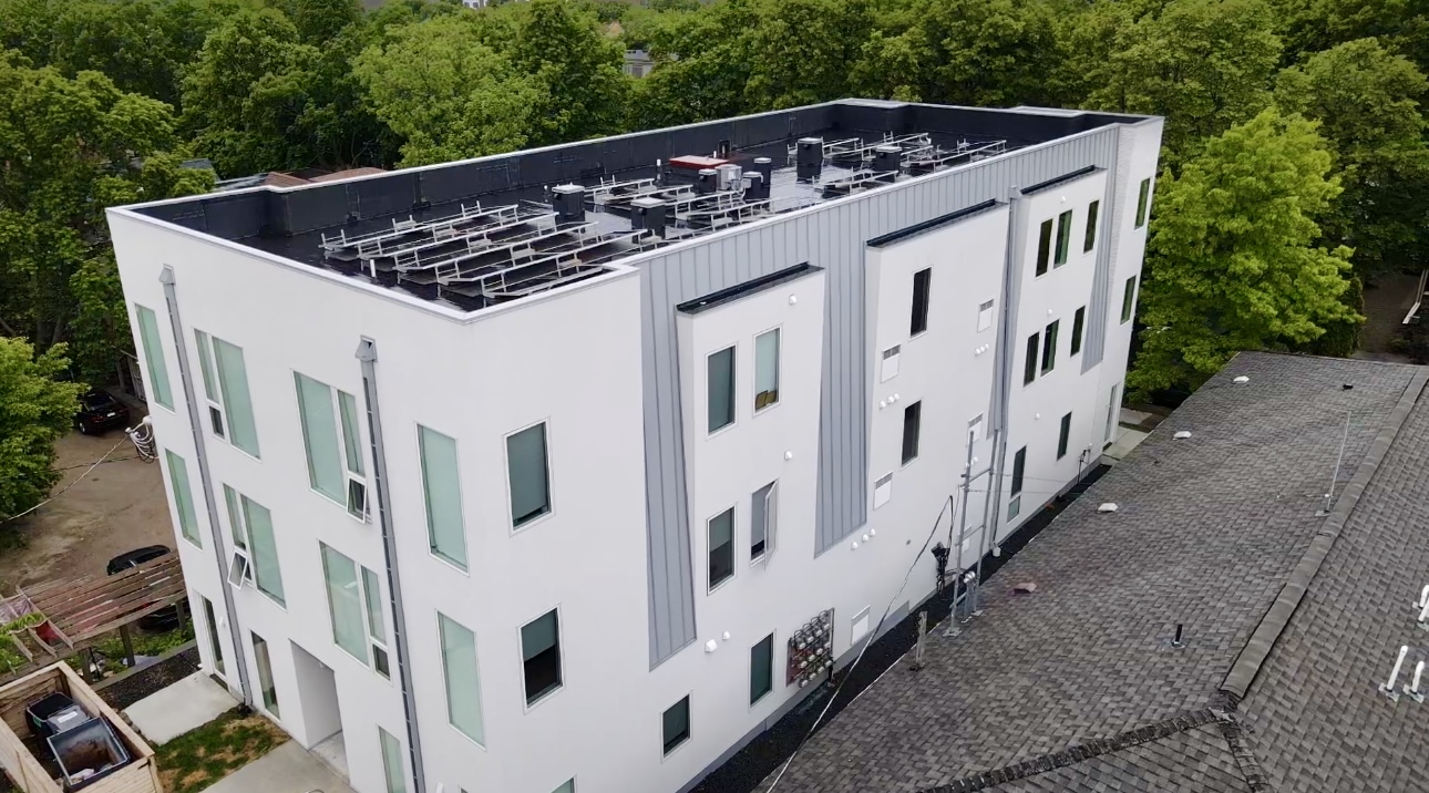 Corner view of multi-family building in Minneapolis featuring a finished flat roof with solar integration.
