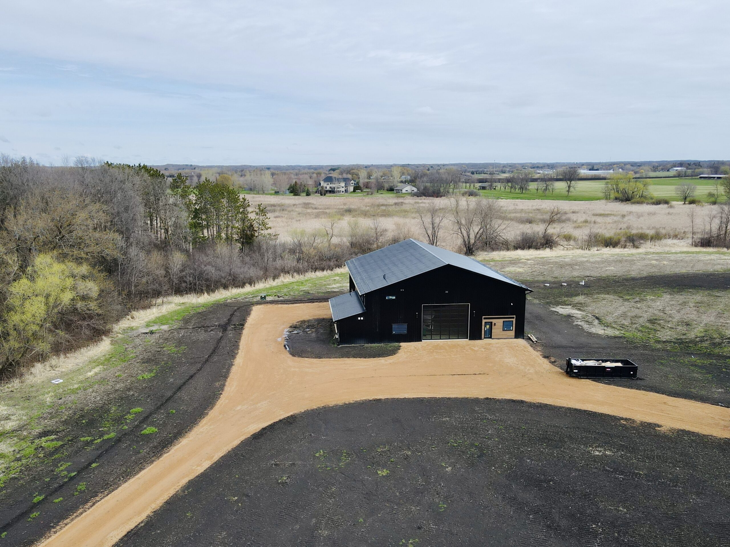 Wide aerial view of a black-roofed building surrounded by open land in Maple Lake, MN.