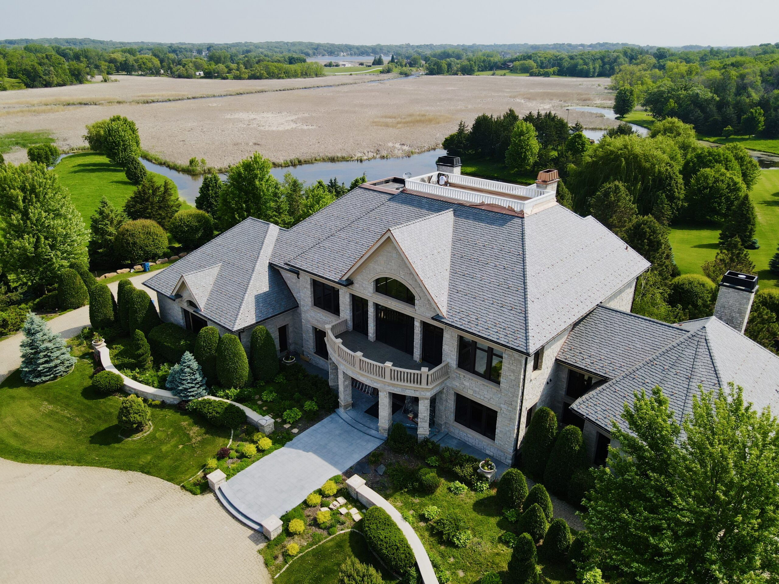 Stunning slate roof on a custom home in Minnetrista, MN, overlooking natural wetlands and lush greenery.