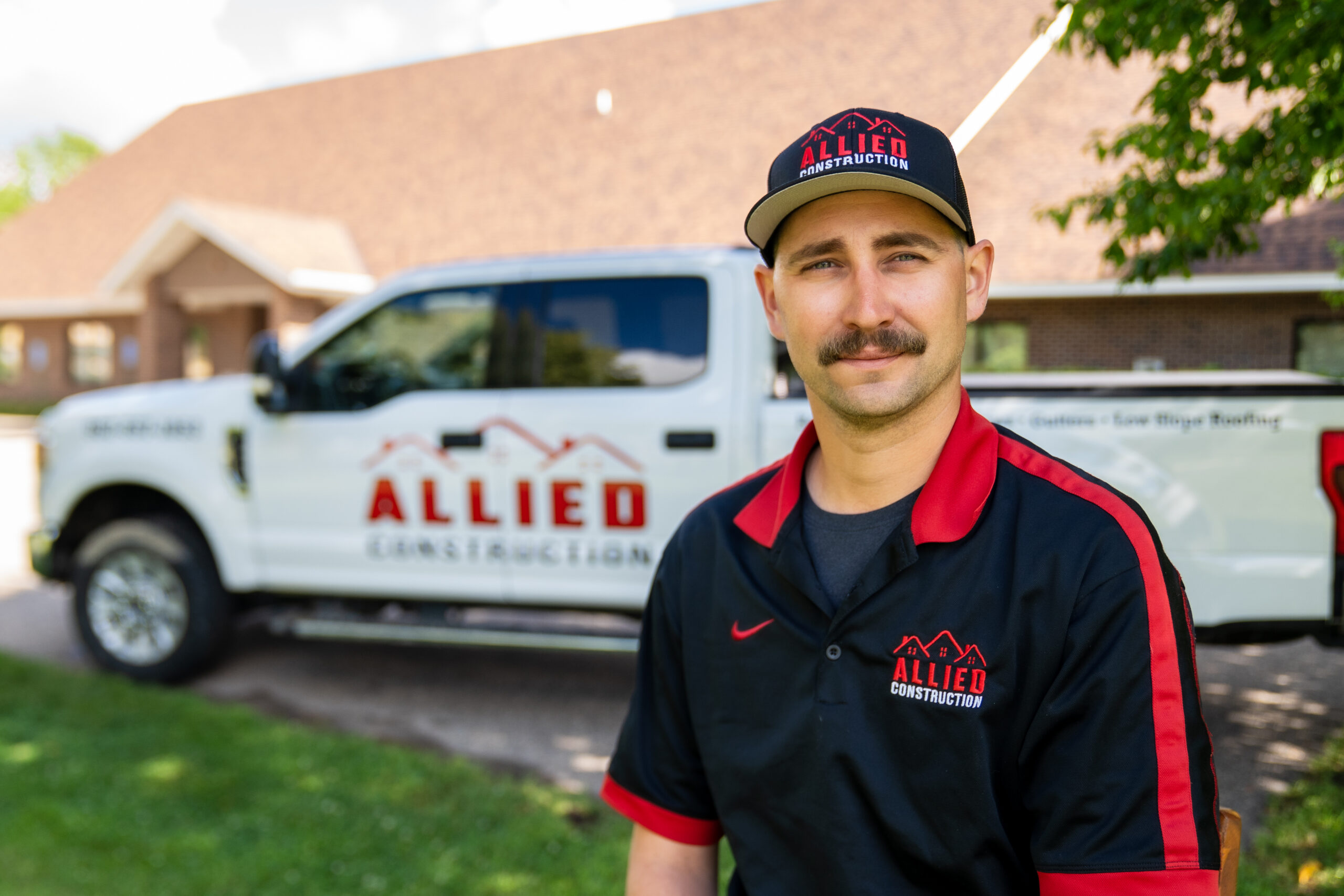 Allied Construction crew member in uniform sitting in front of company truck
