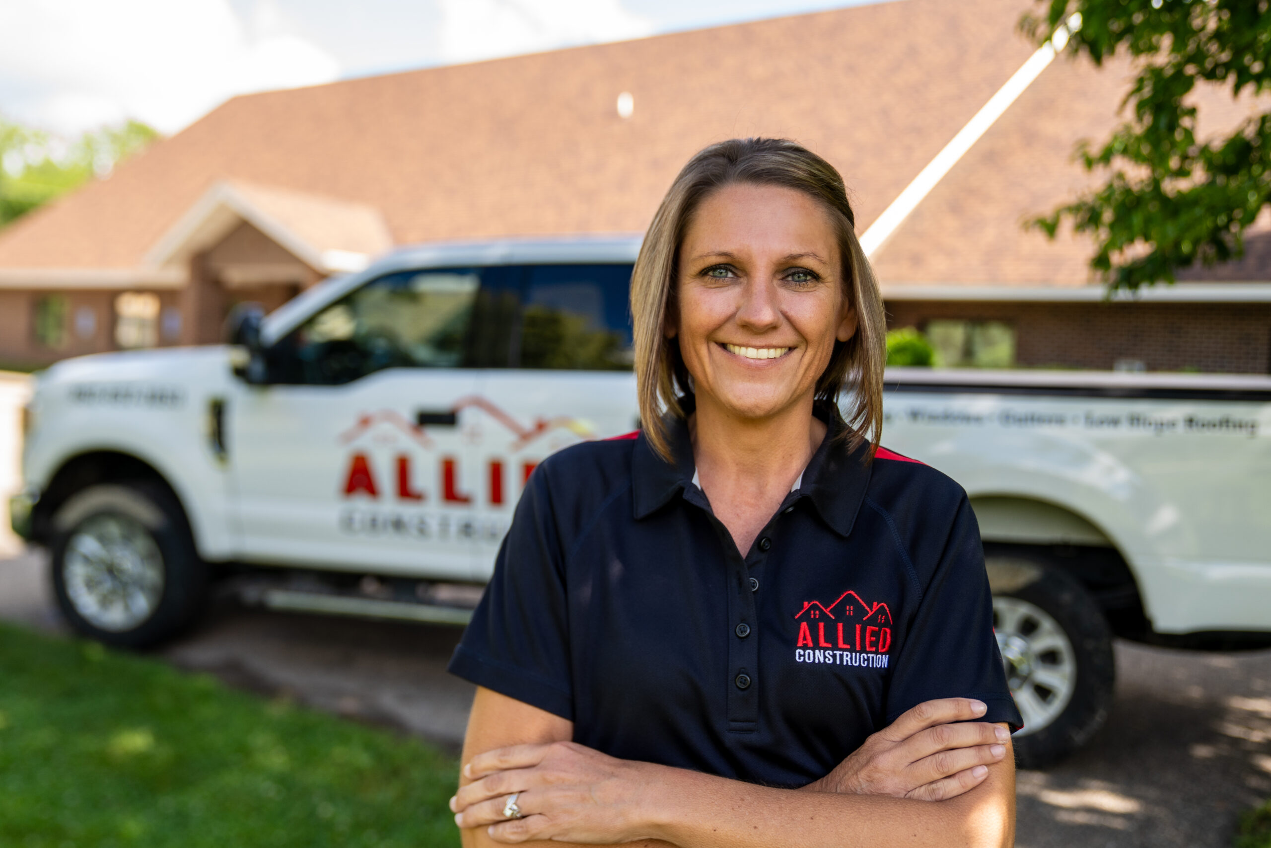 Natalie, Allied Construction’s Office Manager, smiling in front of an Allied truck.