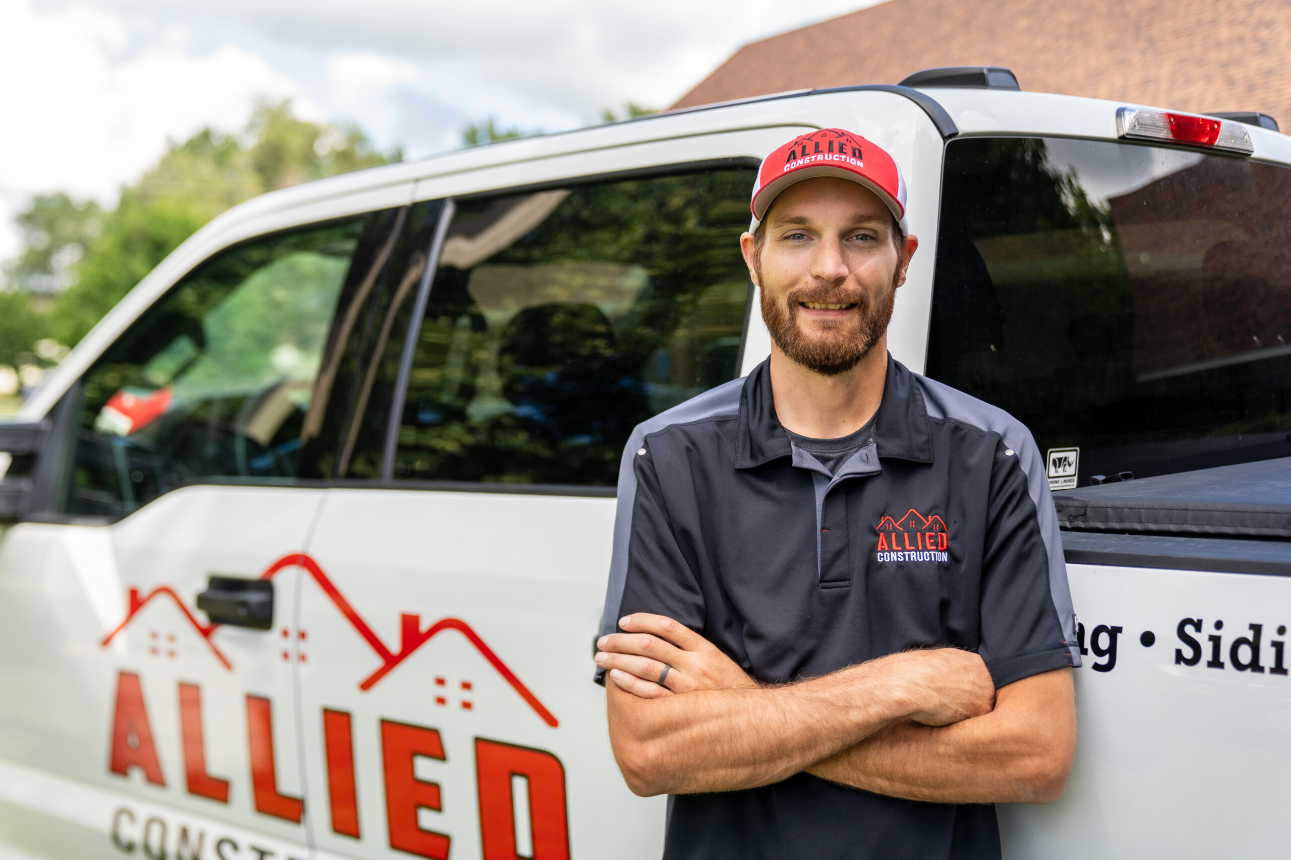 Jordan from Allied Construction standing in front of a branded company truck.