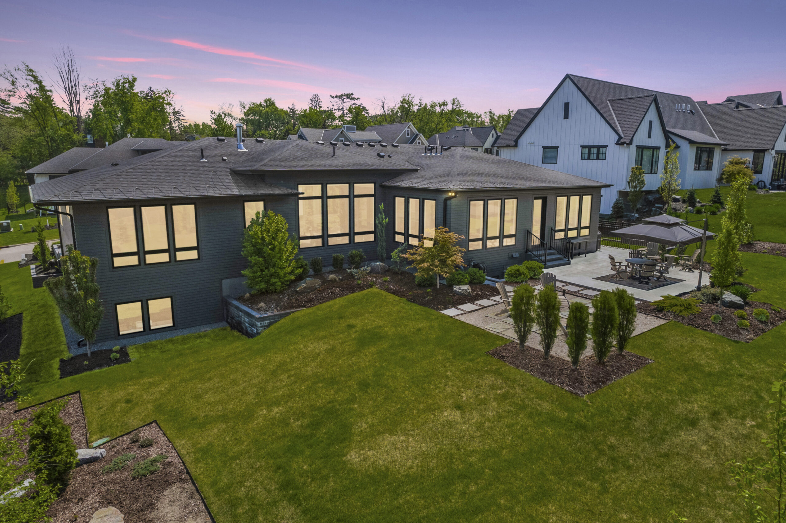 Modern home exterior at sunset featuring updated roofing, large energy-efficient windows, and landscaped backyard