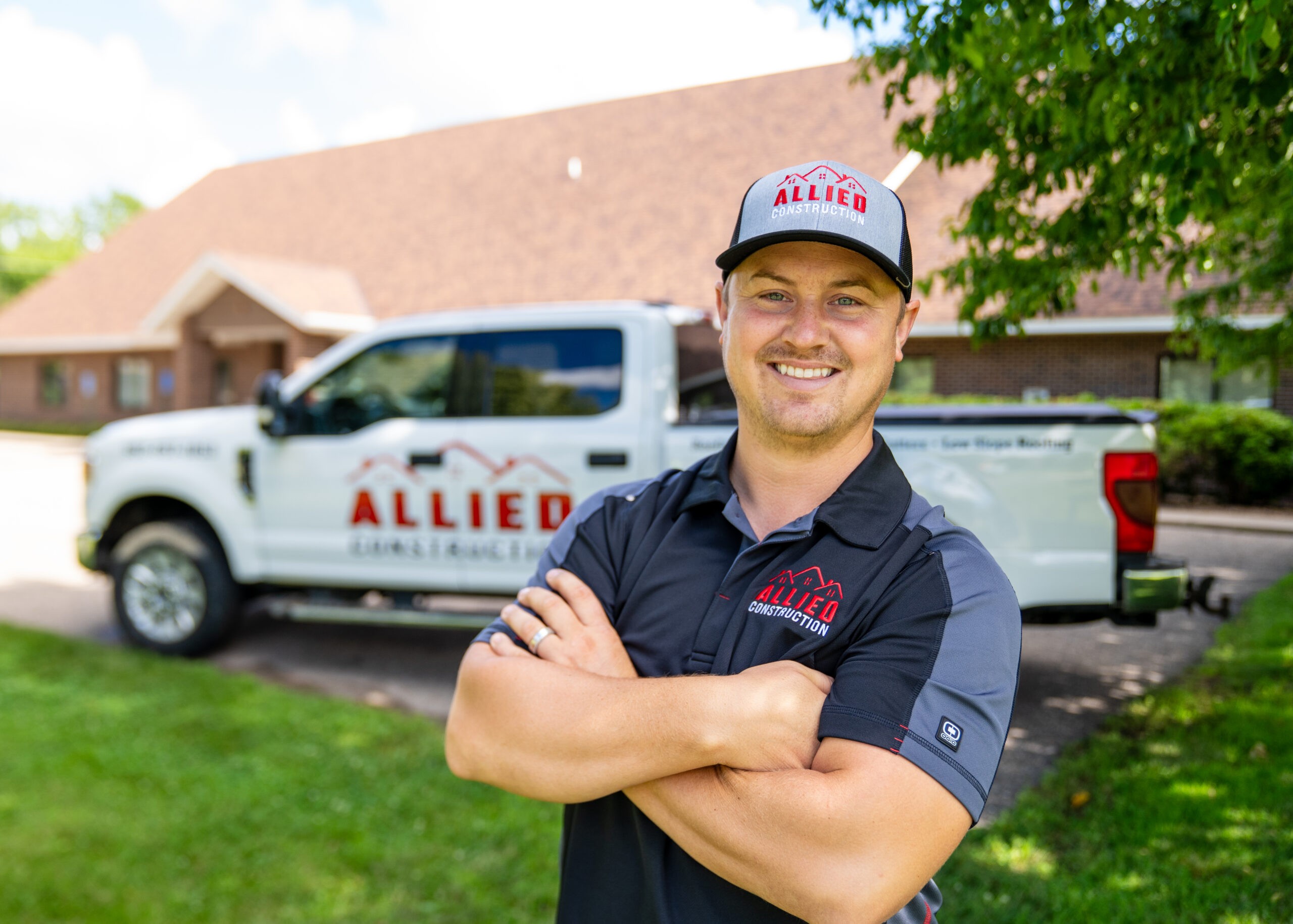 Allied Construction team member smiling in front of branded company truck