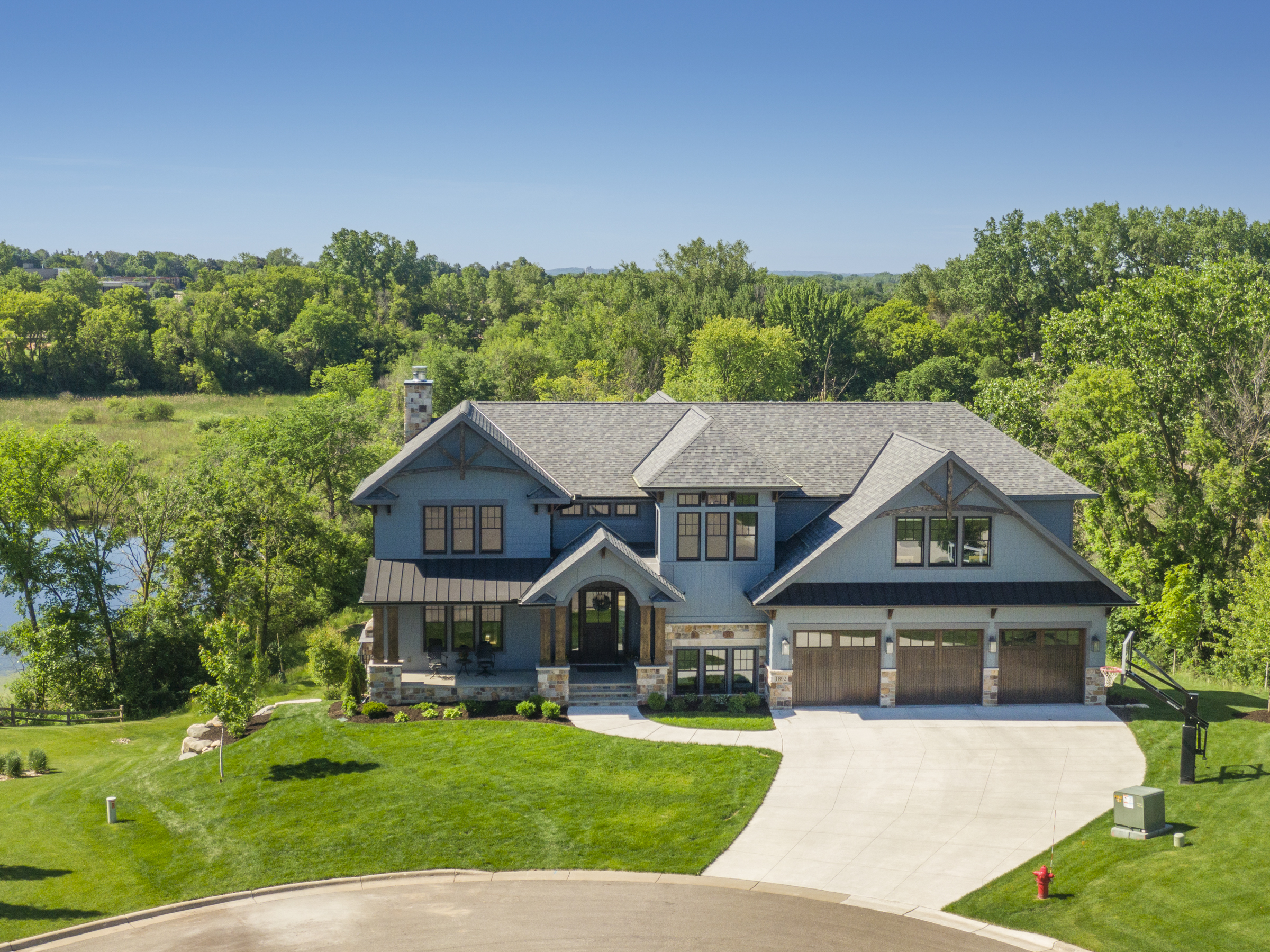 Aerial view of a custom Minnesota home with a newly installed gray asphalt shingle roof by Allied Construction