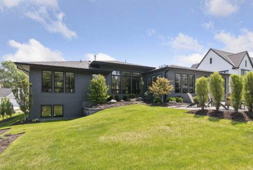 Modern roofing installed on a luxury home with dark siding and a landscaped backyard.