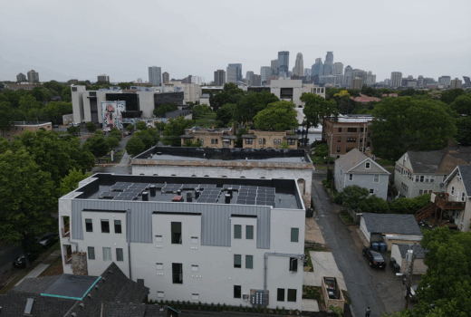 Aerial view of flat roof installation on a Minneapolis building with solar panels and city skyline in the background.