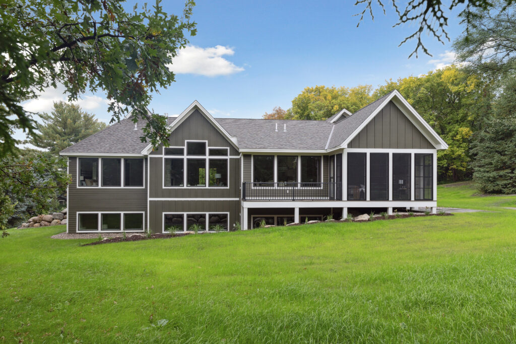 Backside of home with roofing details, screened porch, and natural surroundings.