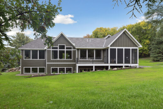 Backside of home with roofing details, screened porch, and natural surroundings.