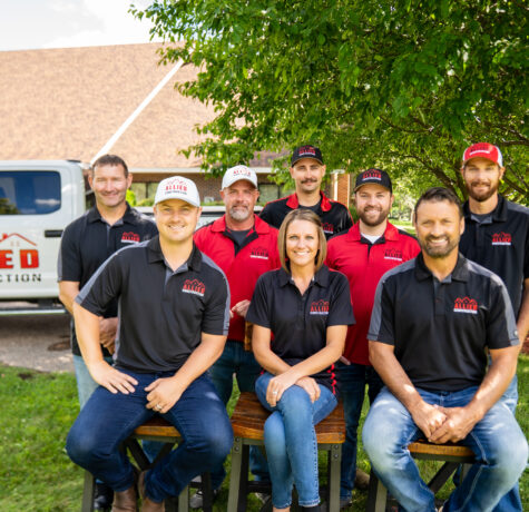 Allied Construction team smiling together outside in front of a branded company truck.