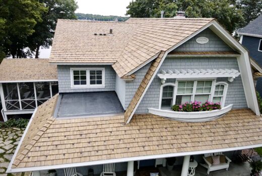 Front view of lakeside home with Brava roof replacement and gray siding.