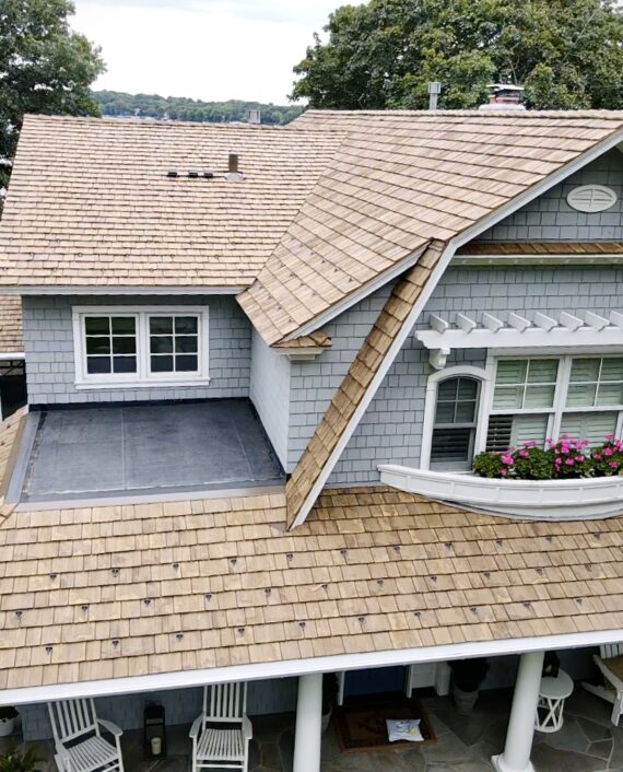 Front view of lakeside home with Brava roof replacement and gray siding.